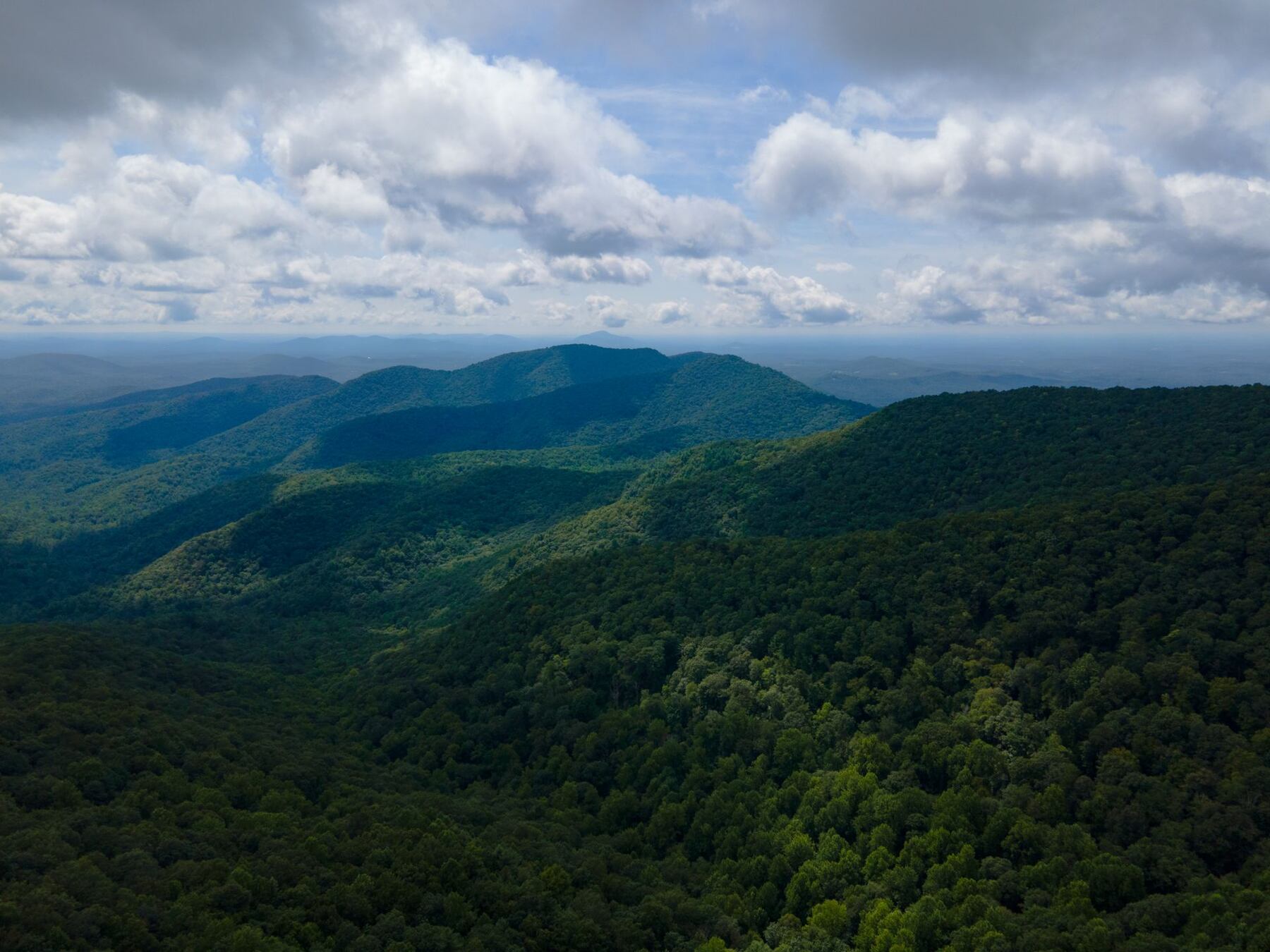 Aerial view of lush green forested mountain ridgelines in North Georgia fading into blue haze
