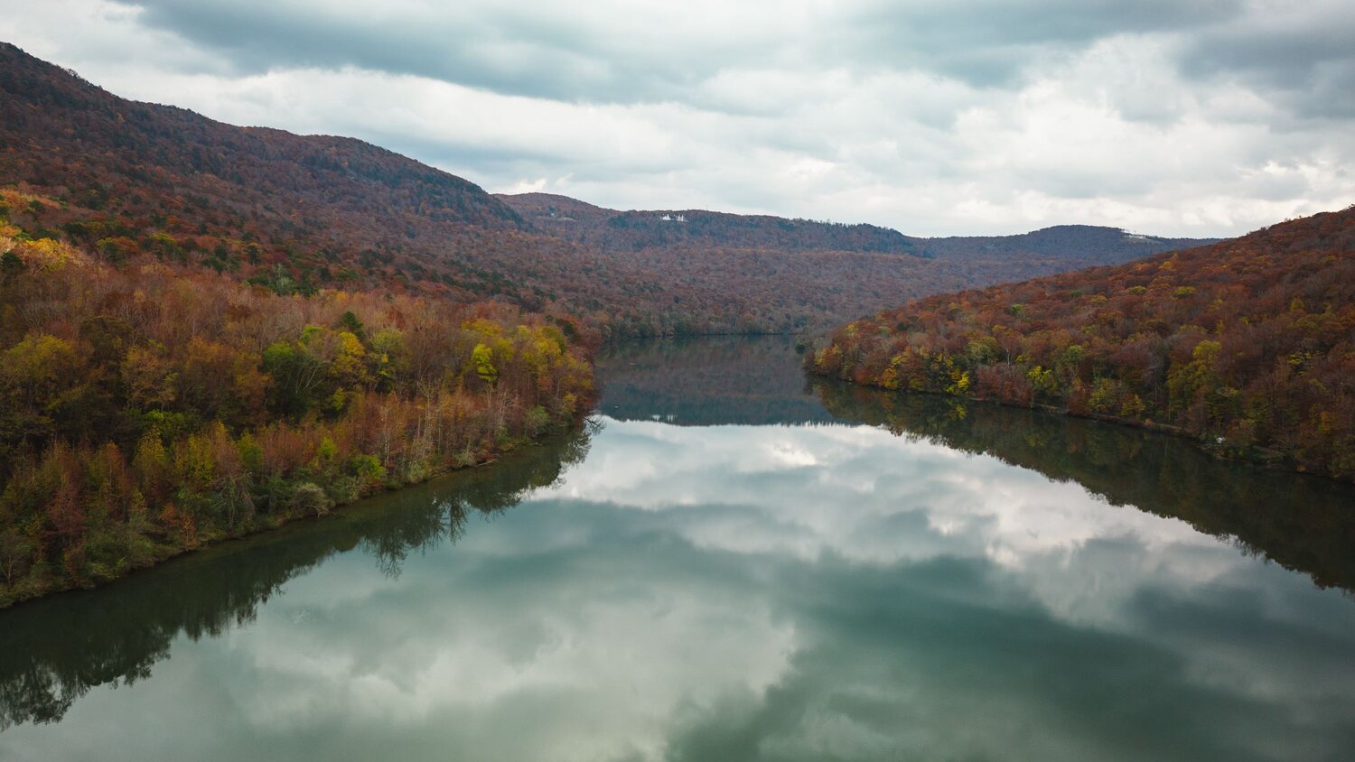 A river winding between wooded ridges in autumn colour